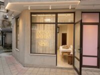 Storefront for IKIGAI ENERGY with a lotus logo on the window; open door reveals a massage table and neatly folded towels inside.