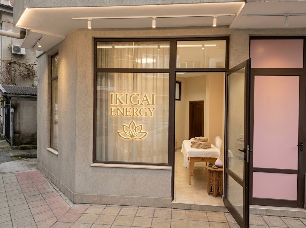 Storefront for IKIGAI ENERGY with a lotus logo on the window; open door reveals a massage table and neatly folded towels inside.